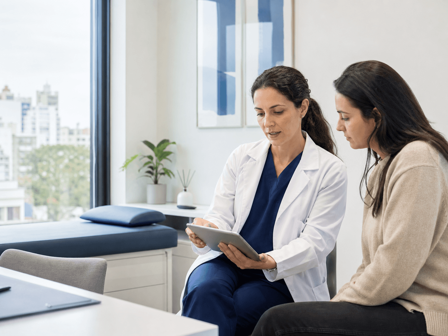 Profesional médica revisando información junto a una paciente